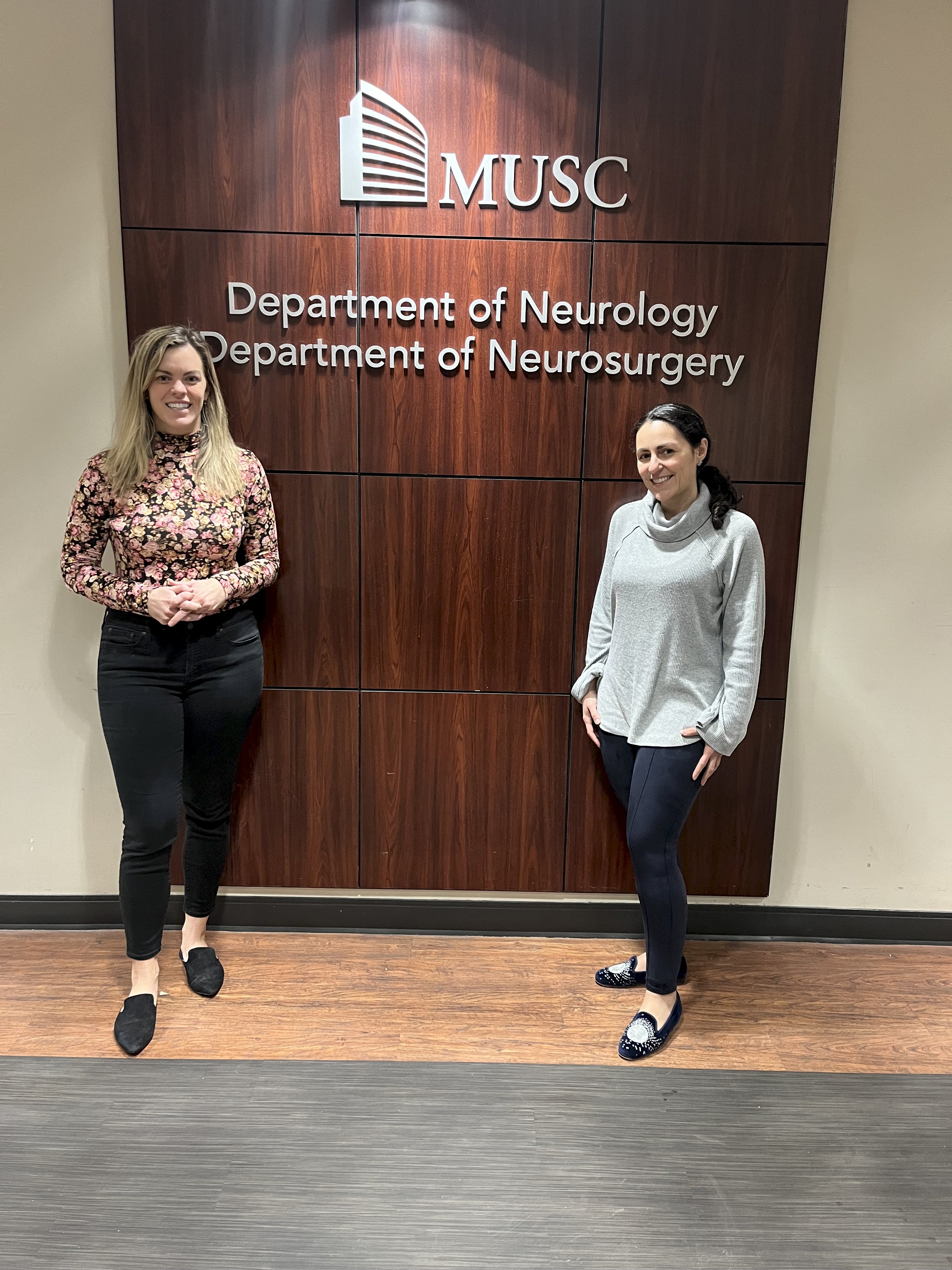Photo shows two people in front of a wooden sign annoucing the MUSC department of neurology  and department of neurosurgery