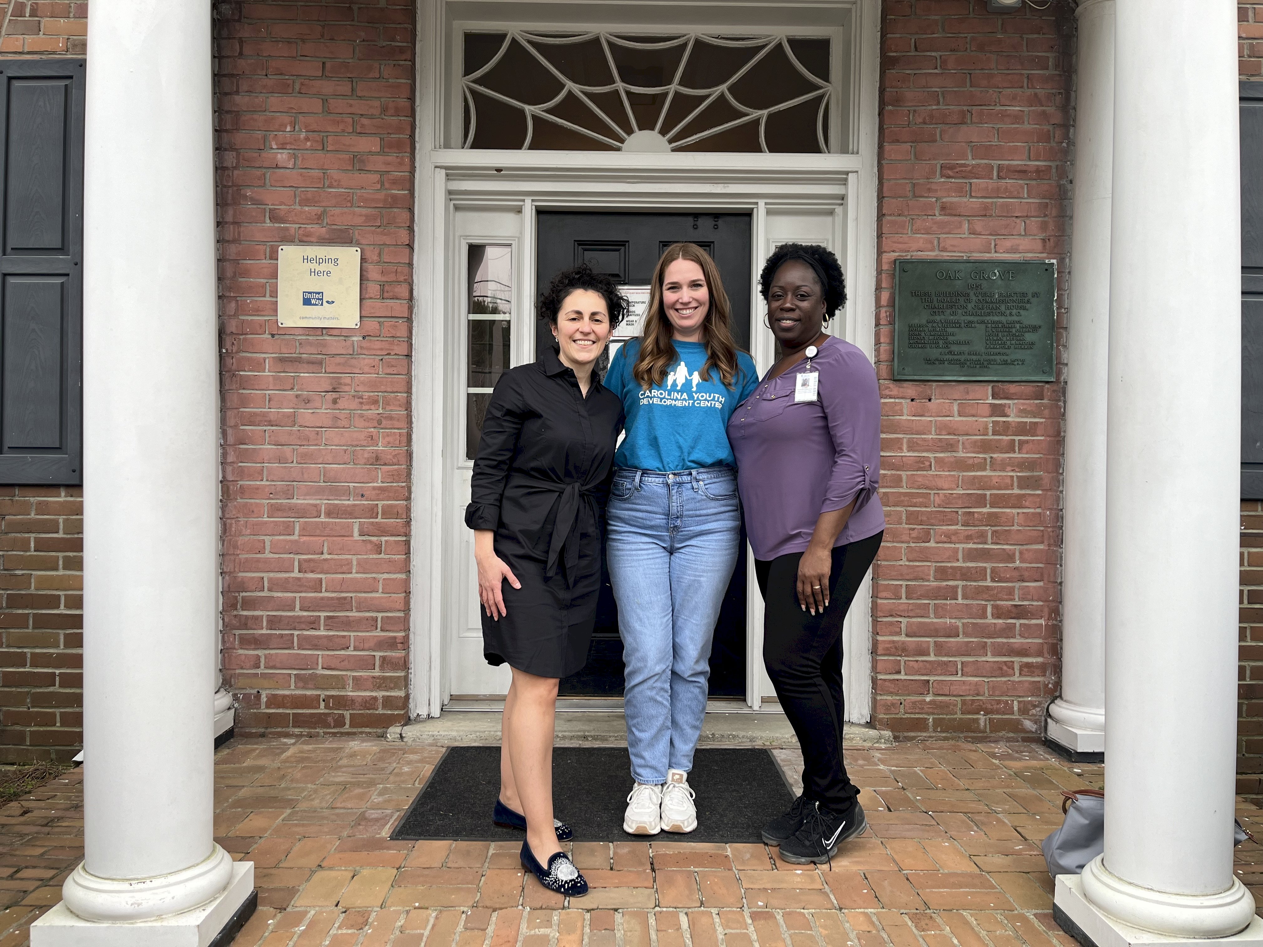 Photo shows three people in front of a grant front entrance to an old South Carolina building - the home of the Carolina Youth Development Center