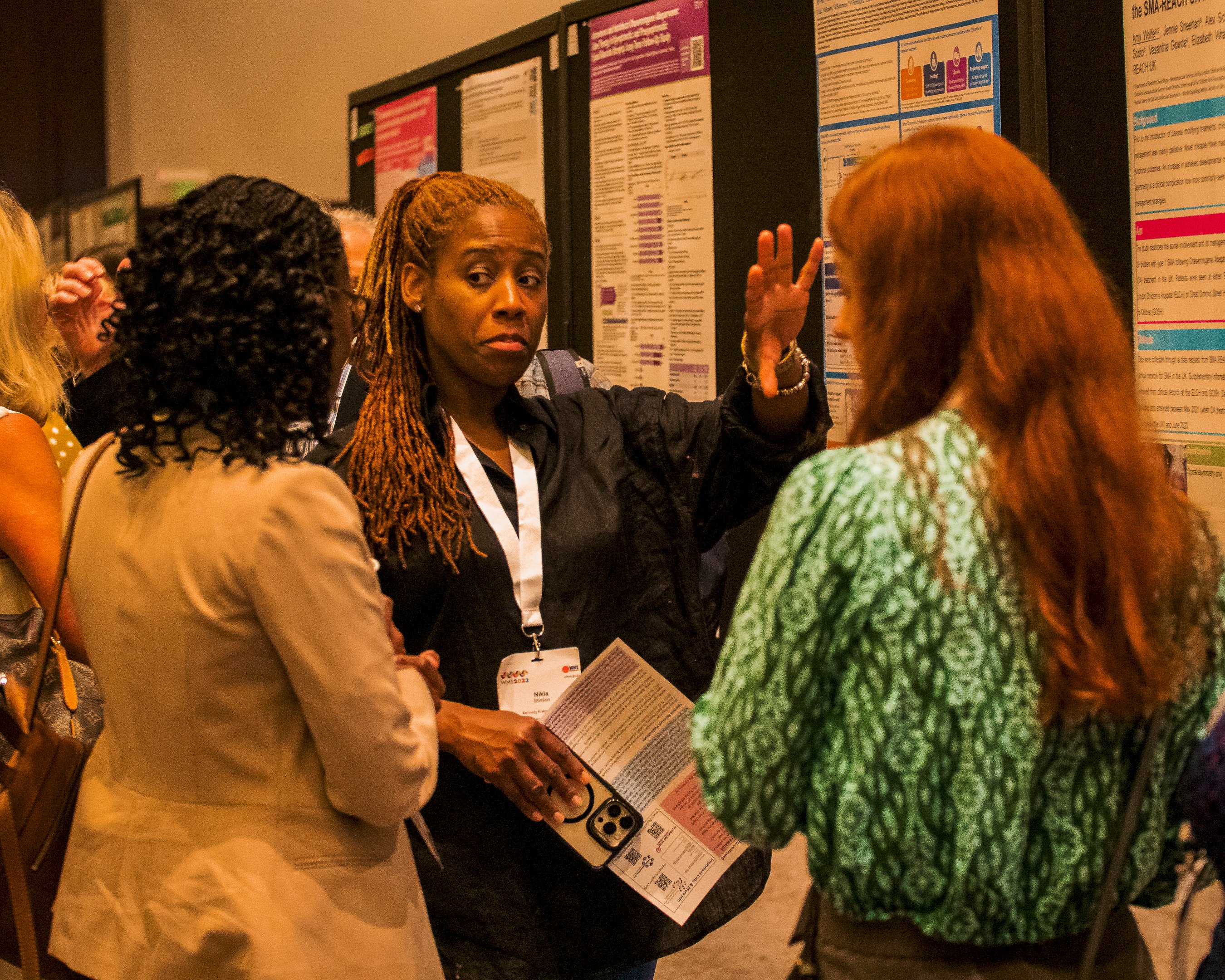Image shows three people gathered at a poster presentation